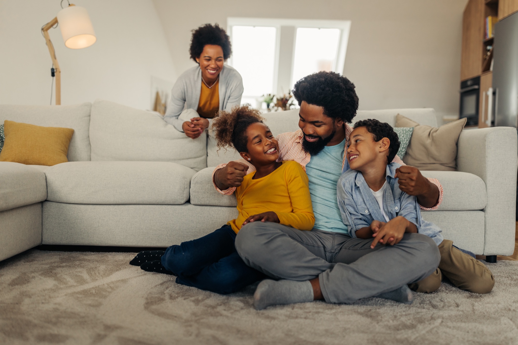 Family laughing together on the living room floor