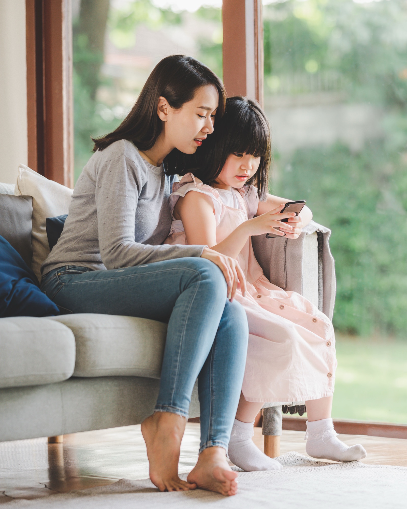 Mother and daughter looking at a phone together on the sofa