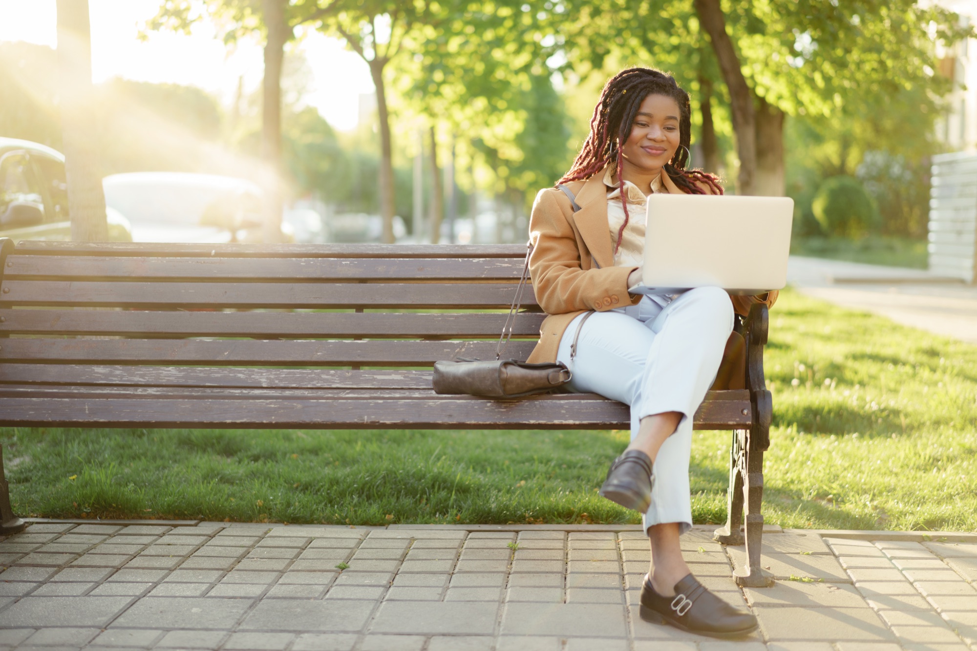 Woman working on a laptop from a park bench