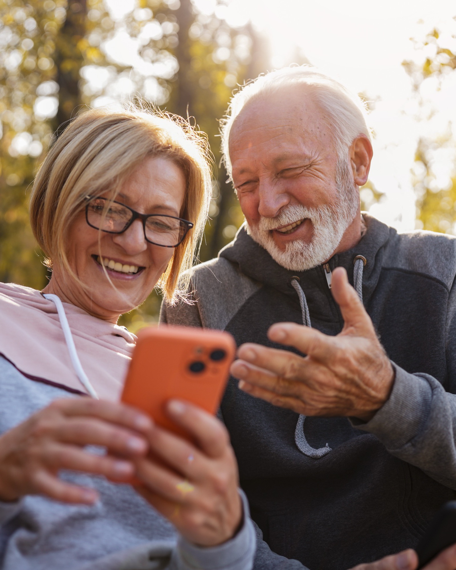 Couple laughing at a phone on a park bench