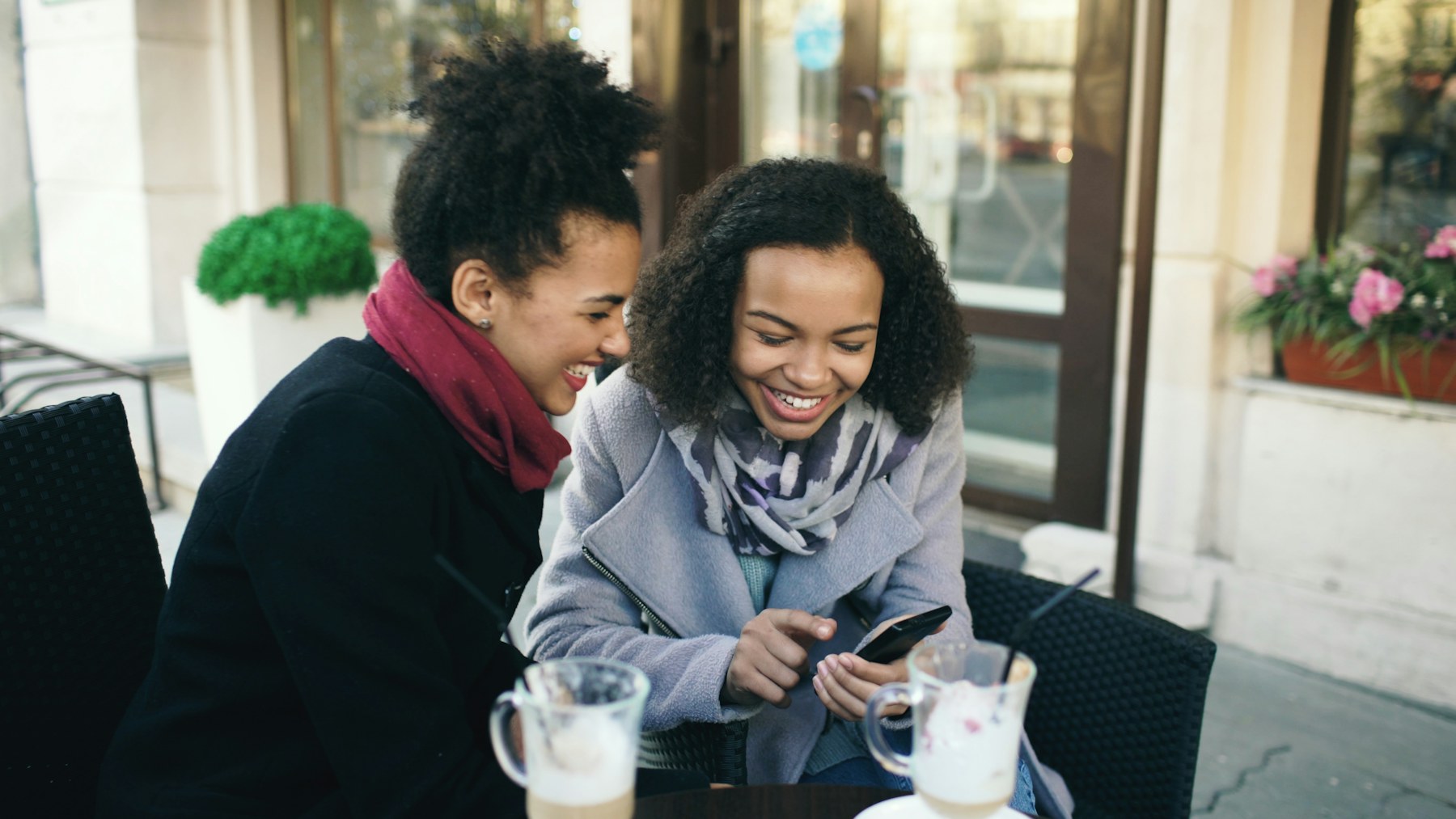 Two young women laughing while looking at a phone