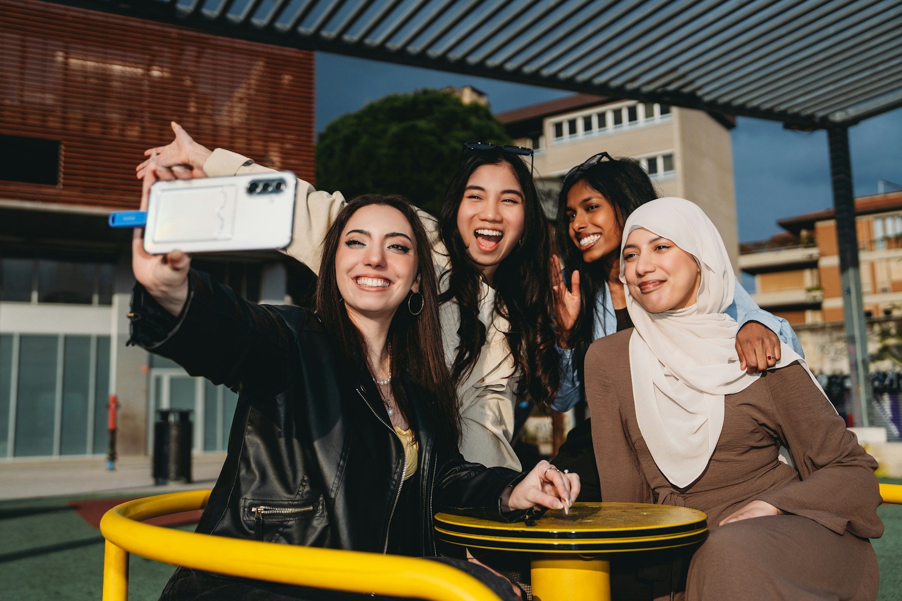 Four happy young women taking a selfie outdoors