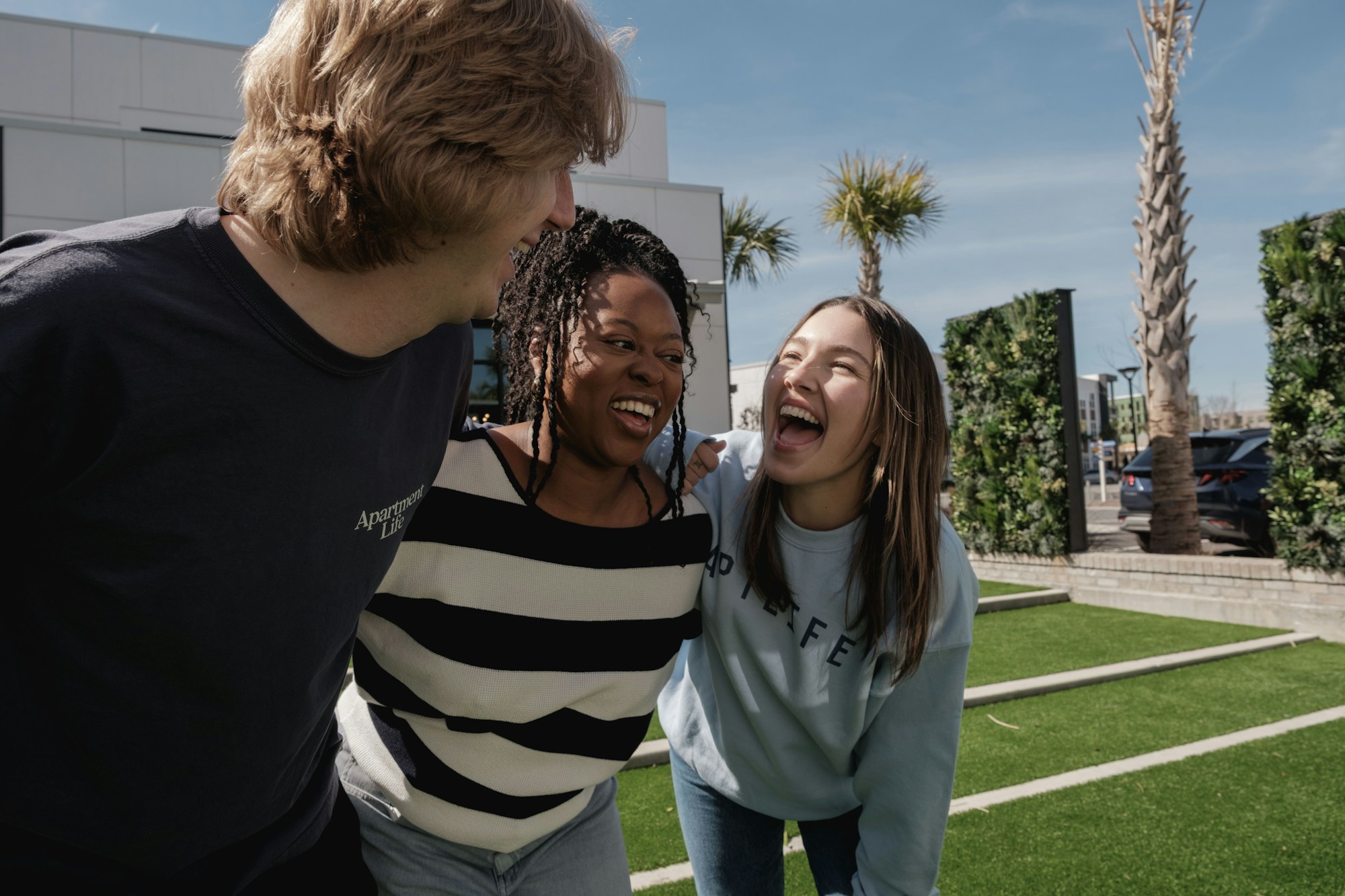 Three friends laughing together outdoors
