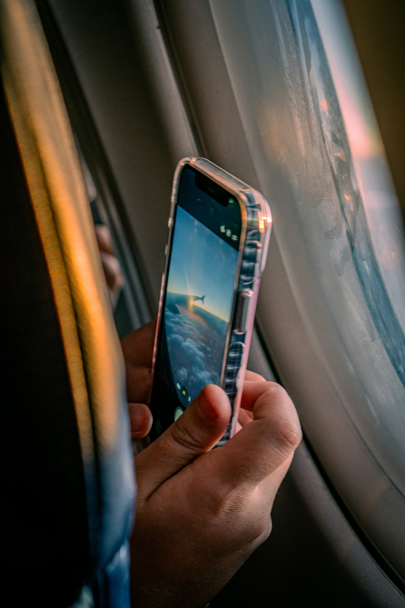 A phone photographing clouds from an airplane window